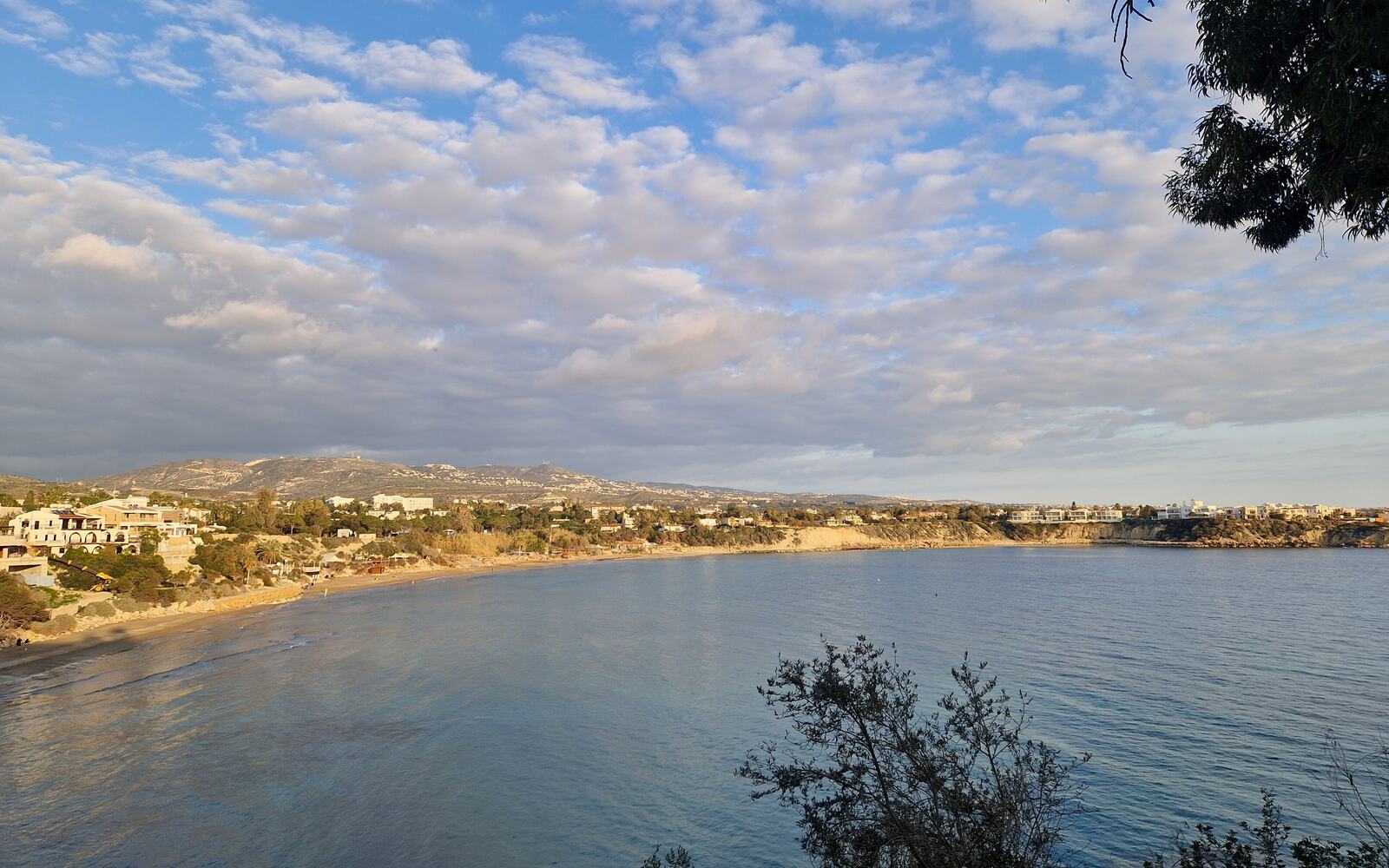Coral Bay near Paphos in the late afternoon, with holiday homes along the curve of the bay and the hills behind